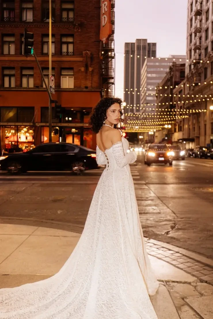 Model is wearing the All Who Wander Hadley gown, a strapless slim A-line dress with detachable long sleeves.