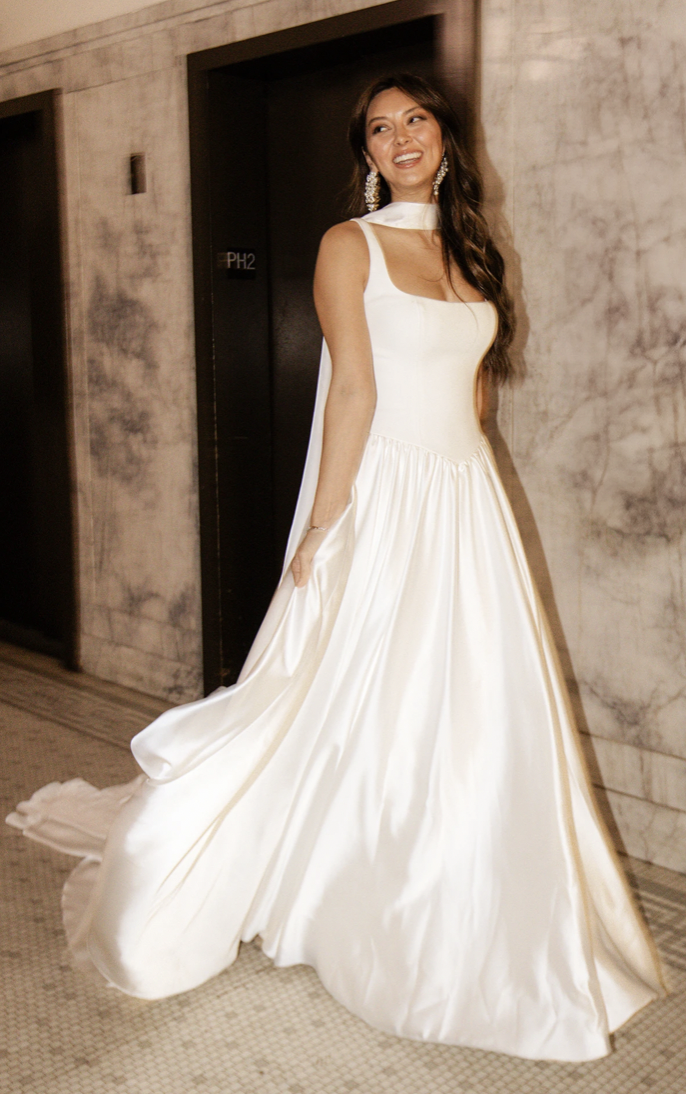 Model is wearing a square neck minimalist basque waist wedding gown