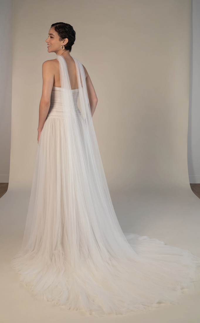 Model is wearing a strapless scoop neck wedding dress with a drop waist